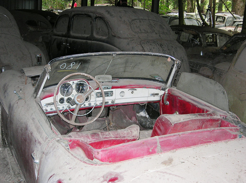 Ein roter Oldtimer 190 SL Mercedes von Staub bedeckt auf dem ehemaligen Autofriedhof Gürbetal