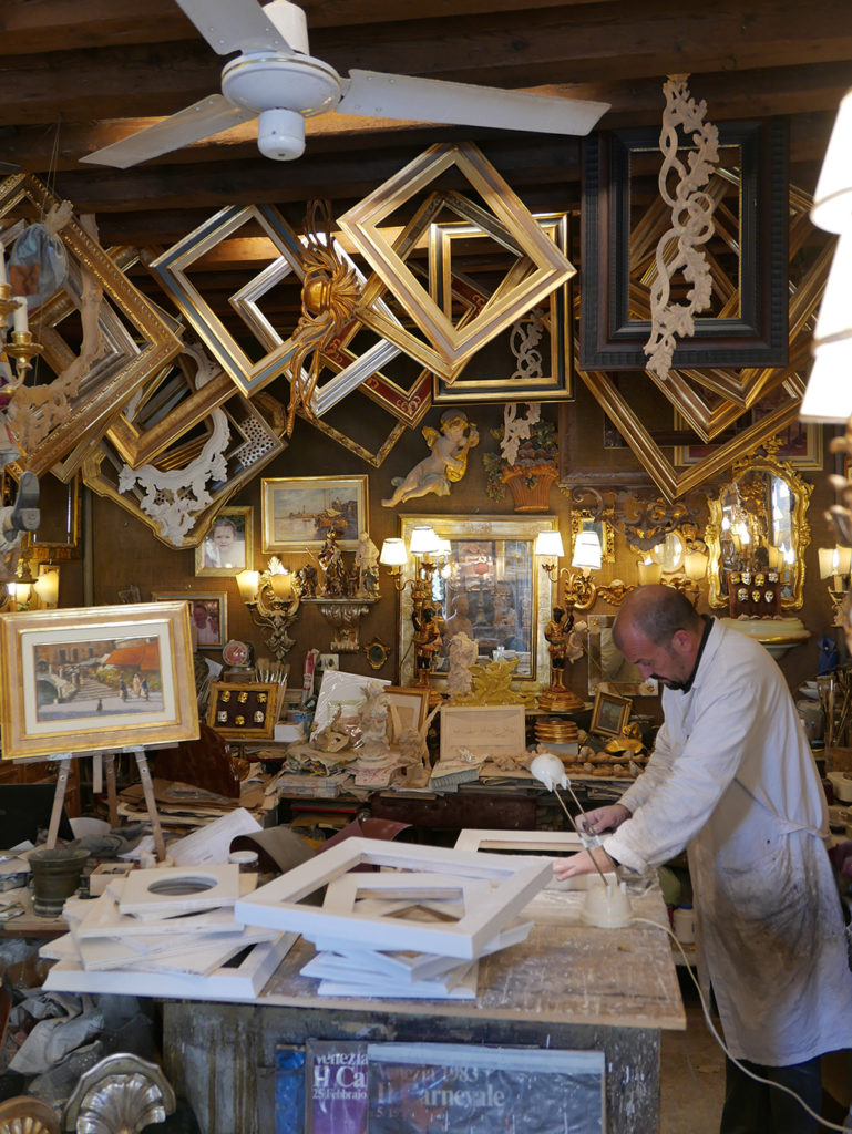 Blick in ein Bilderrahmen-Atelier in Venedig, der Besitzer ist bei der Arbeit.