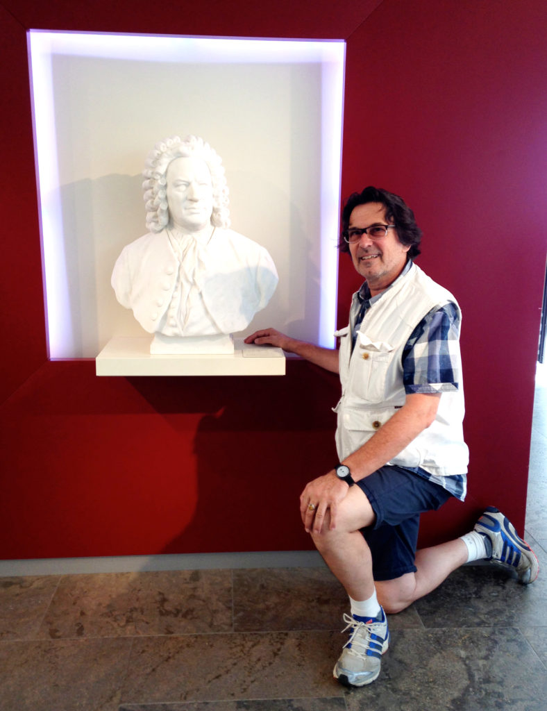 Der Autor der Website kniet vor einer Büste des Komponisten Johann Sebastian Bach.